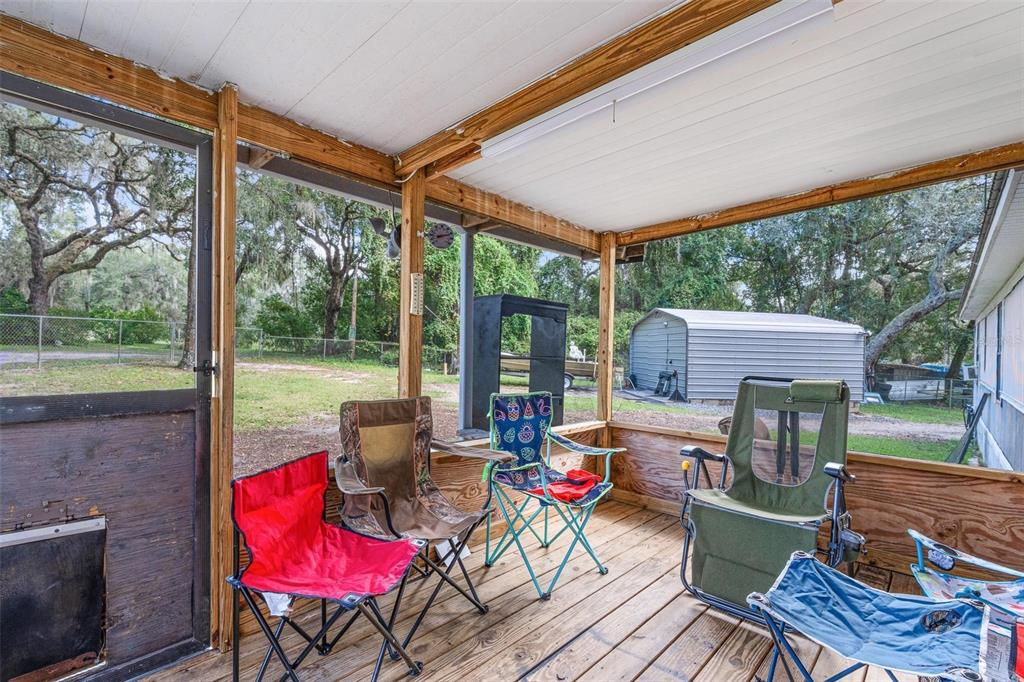 20072 Southeast 155th Place Umatilla, FL 32784 - Photo 13 of 30 a view of a patio with table and chairs potted plants with wooden floor and fence