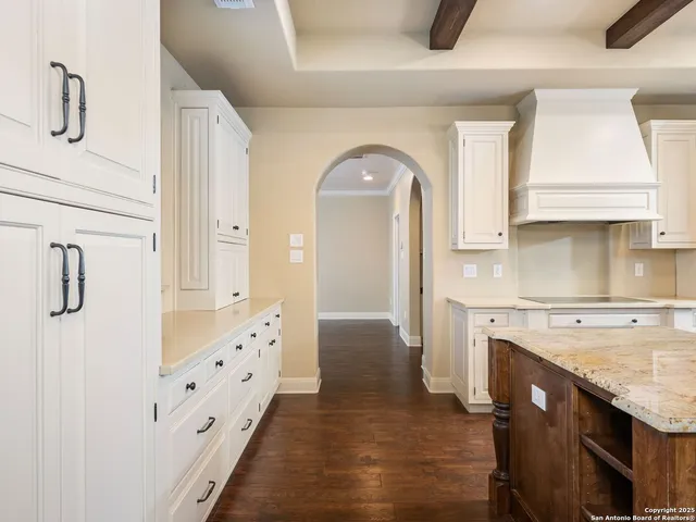 a large white kitchen with a large island oven a stove and a wooden floors