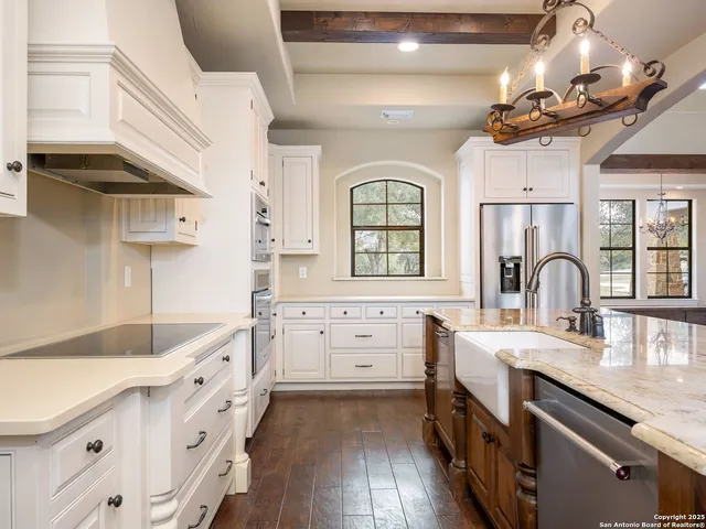 a large kitchen with granite countertop a stove a sink dishwasher a dining table and chairs with wooden floor