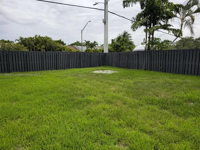 a view of a yard in front of a house with plants and large tree