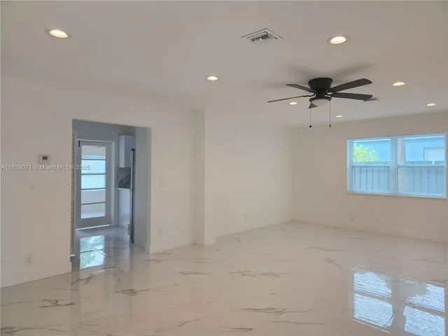 an empty room with a ceiling fan and windows