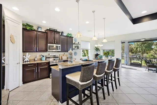 a kitchen with stainless steel appliances granite countertop a table chairs and a refrigerator