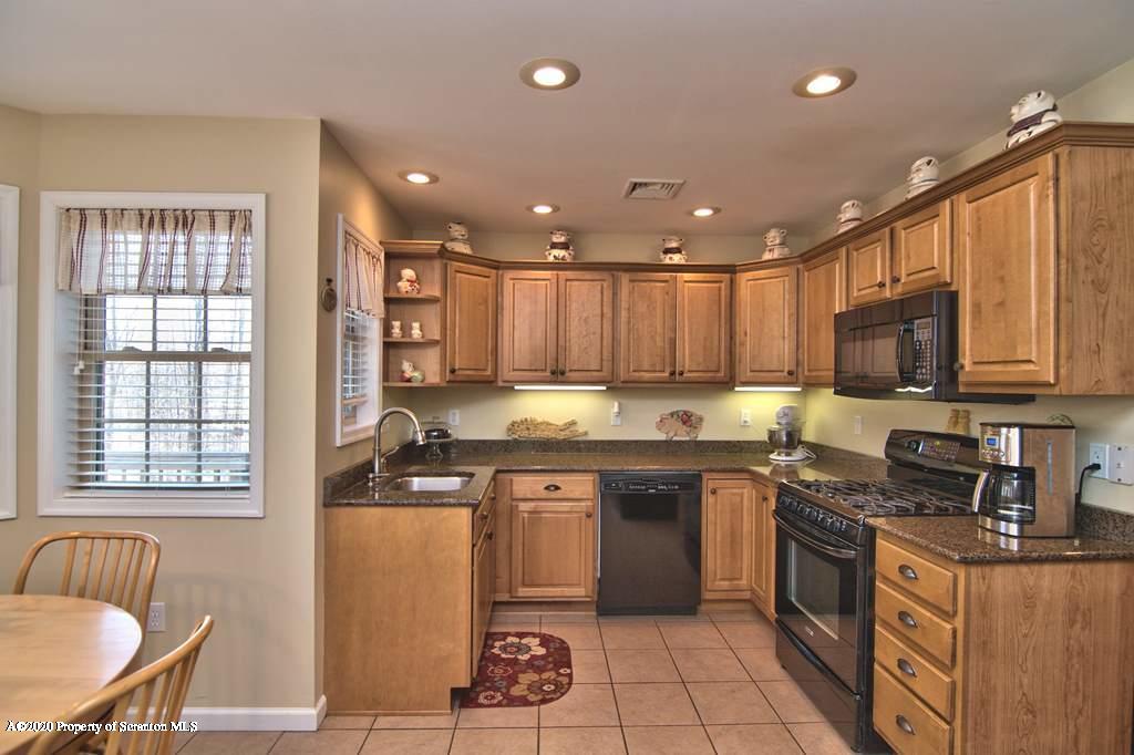 521 Summit Woods Road Moscow, PA 18444 - Photo 20 of 77 a kitchen with stainless steel appliances granite countertop a stove top oven a sink dishwasher a dining table and chairs with wooden floor