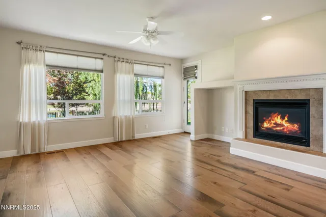 a view of an empty room with wooden floor fireplace and a window