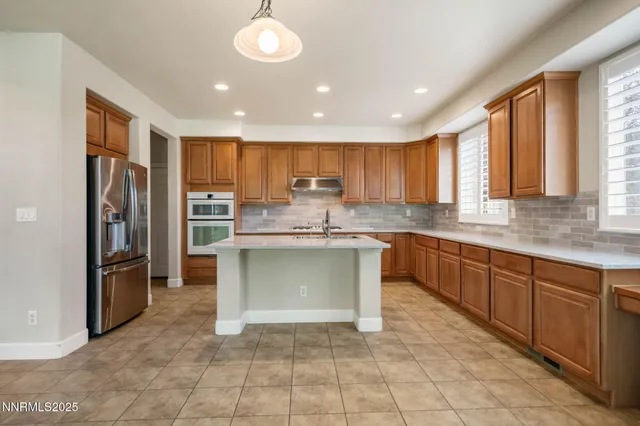 a kitchen with stainless steel appliances granite countertop a refrigerator and a stove top oven