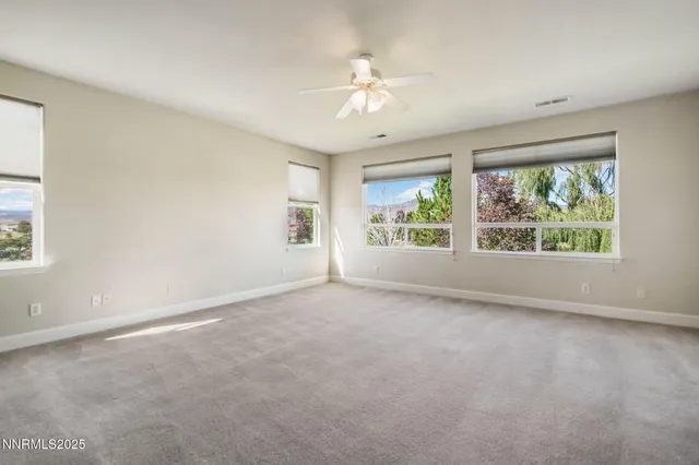 an empty room with windows and chandelier fan