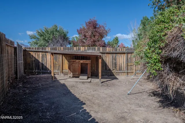 a view of wooden house with large trees and wooden fence