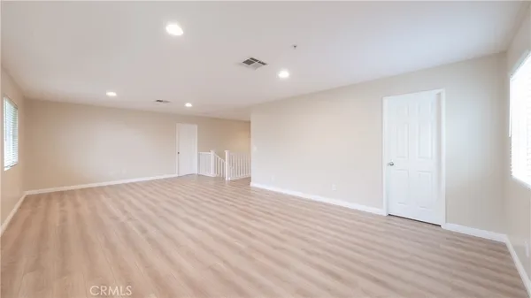 a view of an empty room with wooden floor and closet