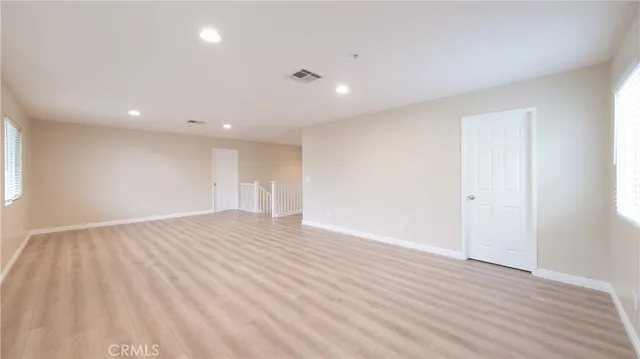 a view of an empty room with wooden floor and closet