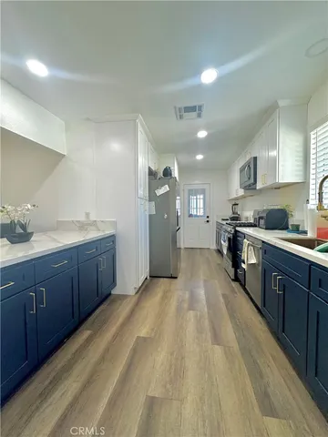a large kitchen with stainless steel appliances lots of counter space and wooden floor