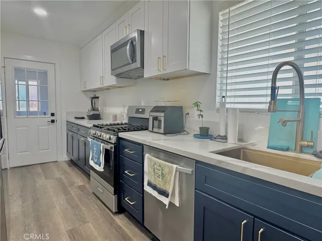 a kitchen with stainless steel appliances granite countertop a sink a stove and a wooden cabinets