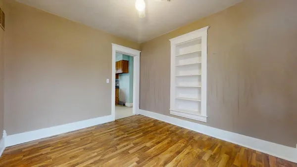 a view of an empty room with wooden floor and a window