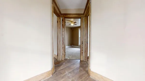 a view of a hallway with wooden floor and a bathroom