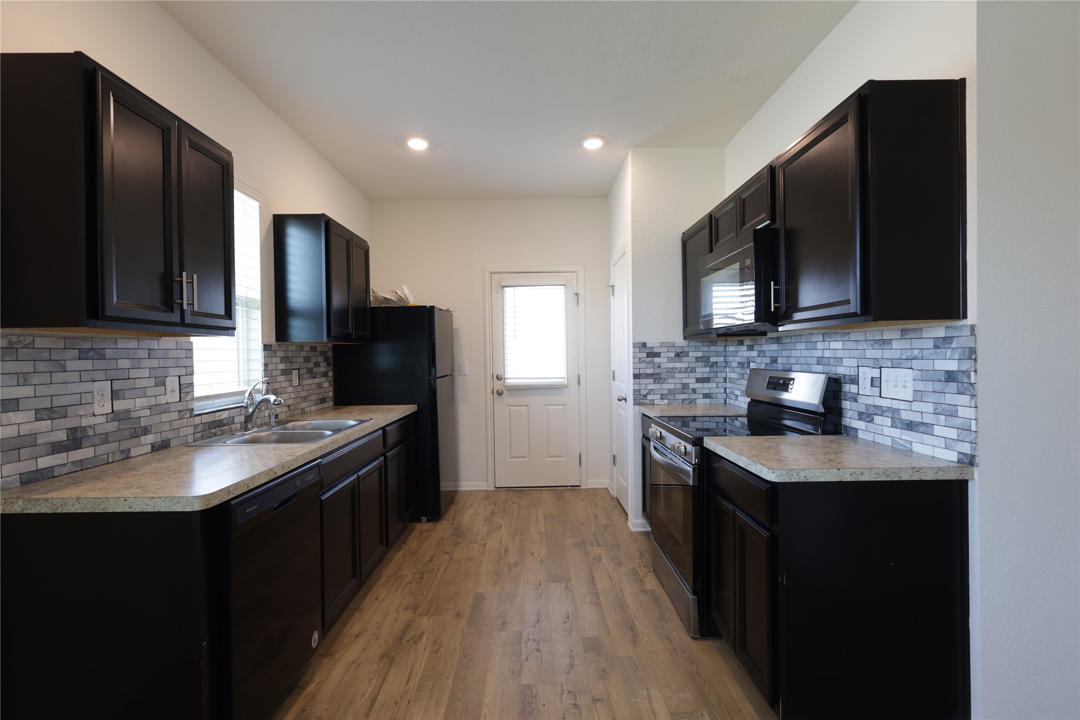 250 Seneca Loop Kyle, TX 78640 - Photo 5 of 22 A well-appointed kitchen features dark cabinetry, ample counter space, and modern appliances, perfect for everyday meal preparation.