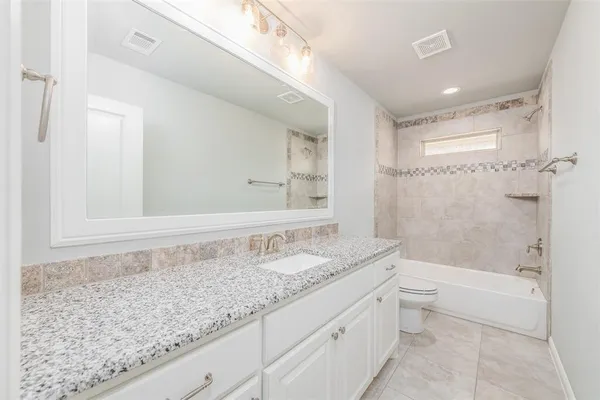 a bathroom with a granite countertop sink a toilet and bathtub