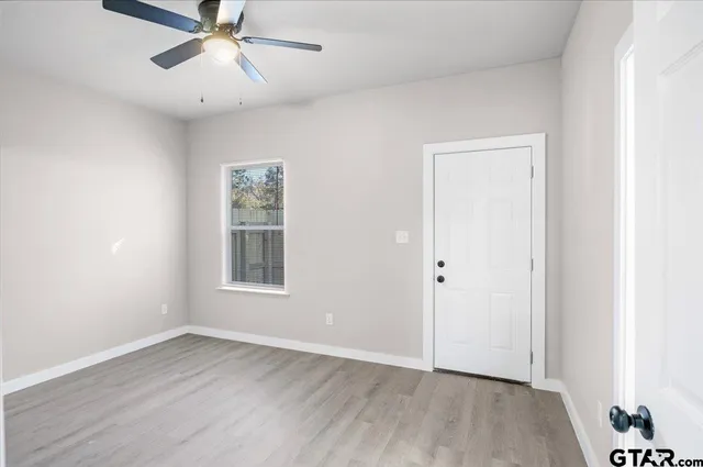 a view of an empty room with wooden floor and a window