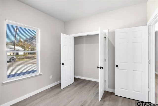 an empty room with wooden floor and windows