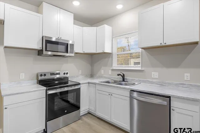 a kitchen with stainless steel appliances granite countertop white cabinets sink and dishwasher