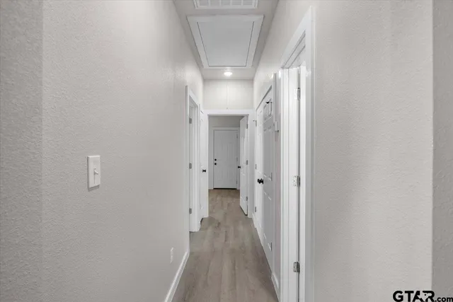 a view of a hallway with wooden floor and a bathroom
