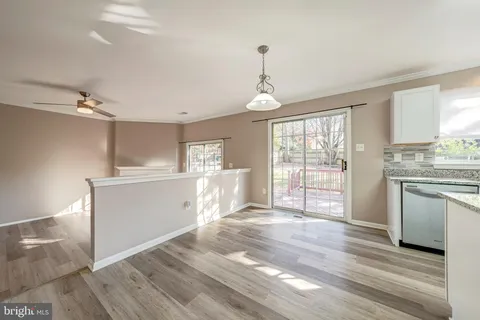 a kitchen with stainless steel appliances granite countertop a stove top oven a sink dishwasher a refrigerator and white cabinets with wooden floor