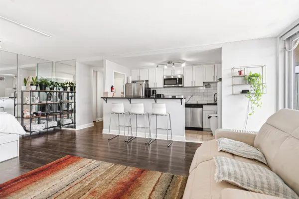 a living room with stainless steel appliances kitchen island granite countertop furniture and a wooden floor