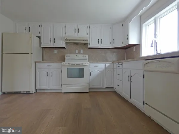 a kitchen with stainless steel appliances granite countertop a refrigerator a stove a sink and white cabinets