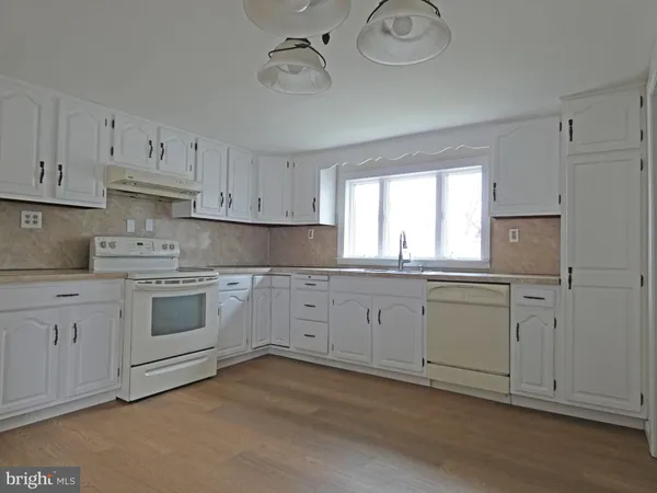 a kitchen with cabinets appliances a sink and a window