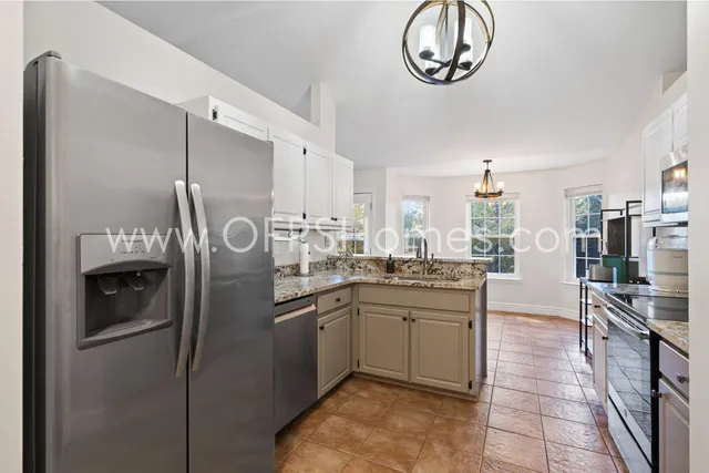a kitchen with stainless steel appliances granite countertop a sink a stove and a refrigerator