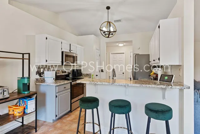 a kitchen with stainless steel appliances granite countertop a sink a stove a refrigerator cabinets and chairs