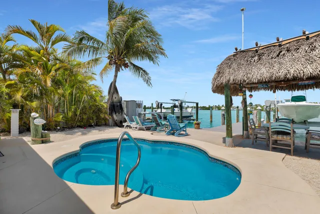 a swimming pool with lawn chairs under an umbrella