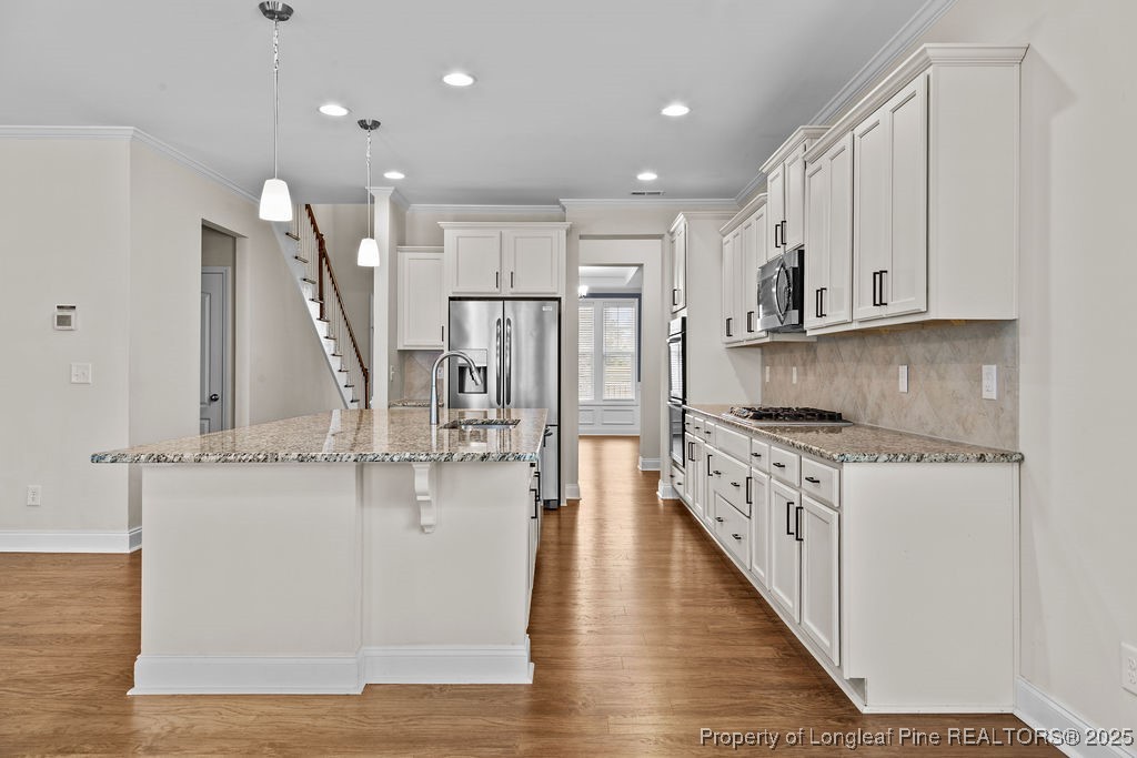 252 School Side Drive Spring Lake, NC 28390 - Photo 7 of 35 a kitchen with stainless steel appliances granite countertop a lot of counter space and wooden floors