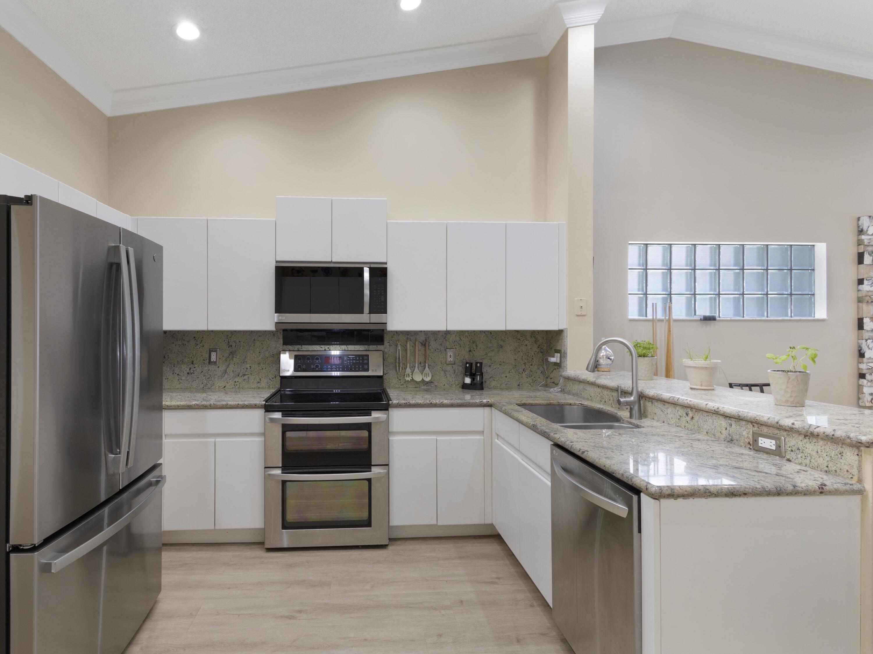 9734 Harbour Lake Circle Boynton Beach, FL 33437 - Photo 4 of 41 a kitchen with stainless steel appliances granite countertop a stove top oven a sink and a refrigerator
