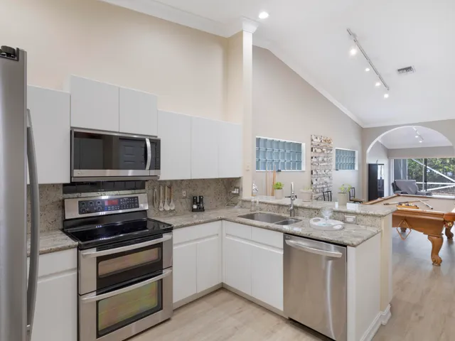 a kitchen with stainless steel appliances granite countertop a refrigerator and a stove top oven