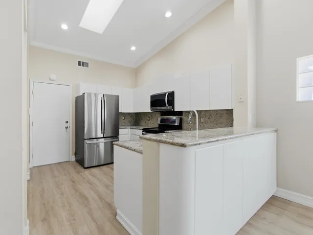 a view of kitchen with stainless steel appliances wooden floor and living room view