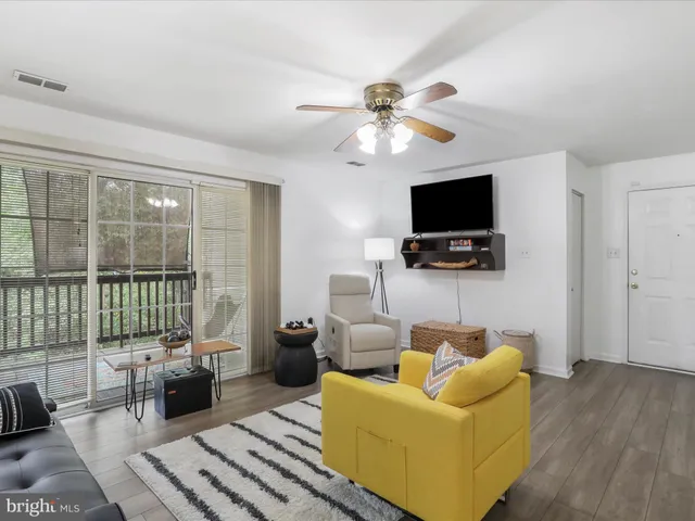 a living room with furniture a flat screen tv and a floor to ceiling window