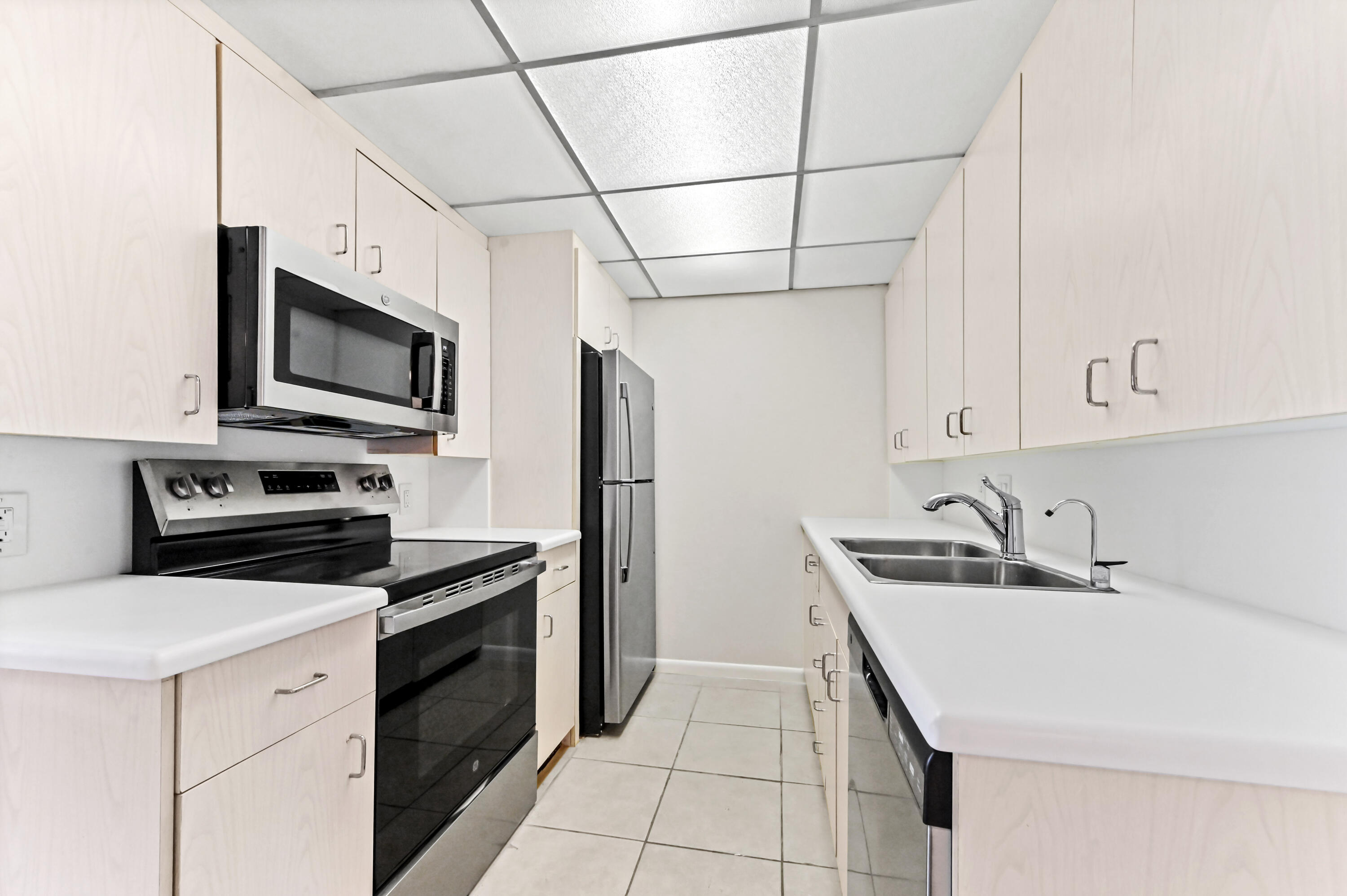 1010 Newcastle A, Unit 1010 Boca Raton, FL 33434 - Photo 6 of 27 a kitchen with a sink stainless steel appliances and white cabinets