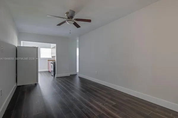 a view of an empty room with a window and wooden floor