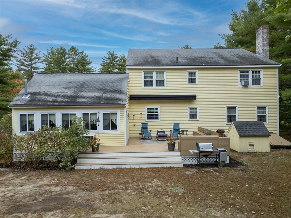 86 Turnpike Road Townsend, MA 01469 - Photo 2 of 42 a view of a white house with large windows and a lawn chairs under an umbrella