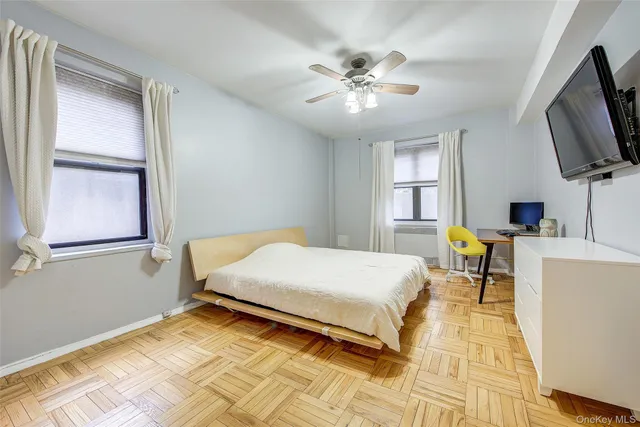 a bedroom with a bed a flat screen tv and windows