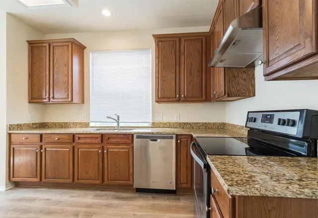 a kitchen with stainless steel appliances granite countertop a stove a sink and a microwave