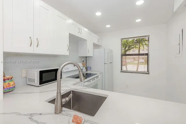 a kitchen with stainless steel appliances granite countertop a stove a sink and a microwave