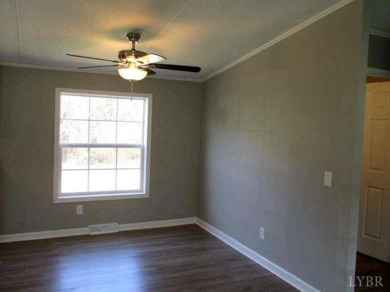 5629 Gladys Road Altavista, VA 24517 - Photo 11 of 29 an empty room with wooden floor chandelier fan and windows