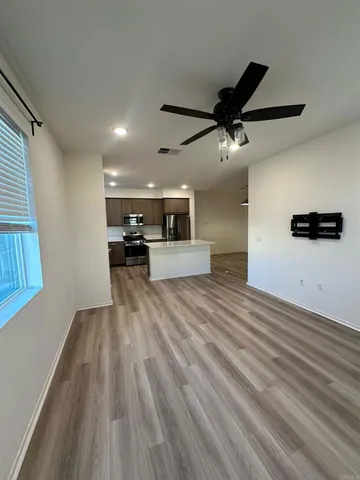 an empty room with a chandelier fan and windows
