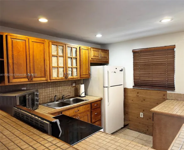 a kitchen with a refrigerator a stove sink and cabinets