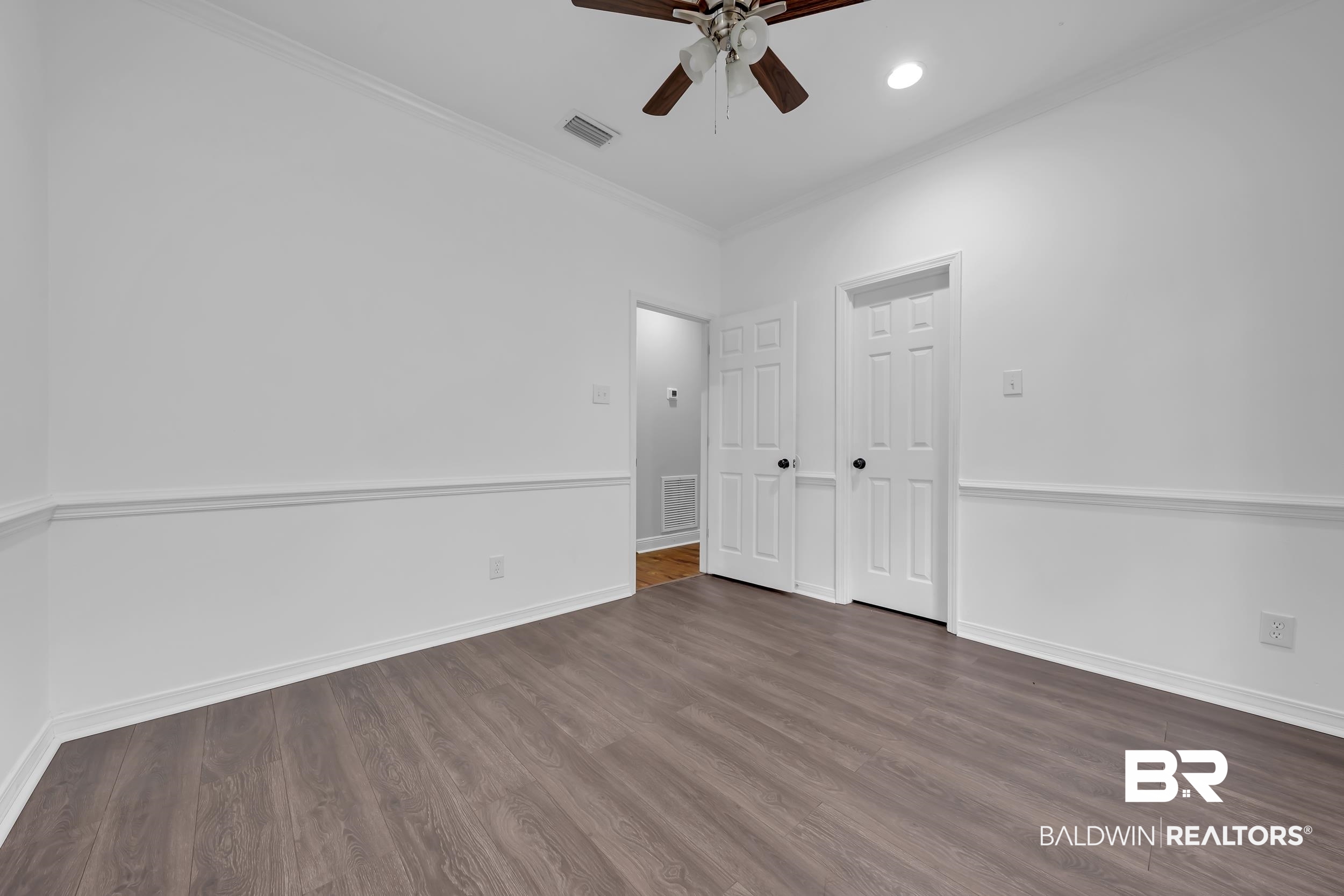 14960 Howells Ferry Road Wilmer, AL 36587 - Photo 18 of 22 Interior room featuring wood-finish flooring, white walls with chair rail molding, and a ceiling fan
