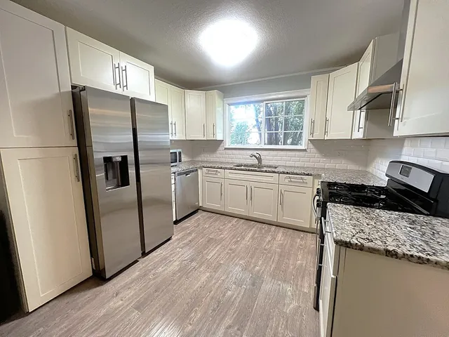 a kitchen with stainless steel appliances granite countertop a sink stove and refrigerator