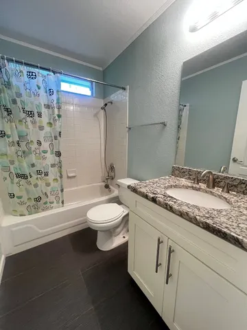 a bathroom with a granite countertop sink toilet and shower
