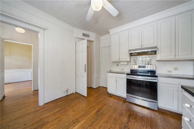 a kitchen with granite countertop a stove cabinets and wooden floor