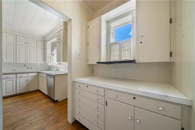 a kitchen with white cabinets a sink and dishwasher with wooden floor