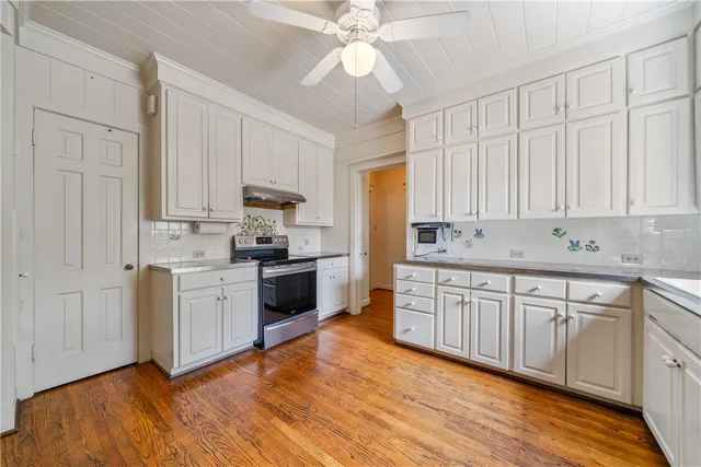 a kitchen with stainless steel appliances granite countertop a stove a sink dishwasher and a refrigerator with white cabinets